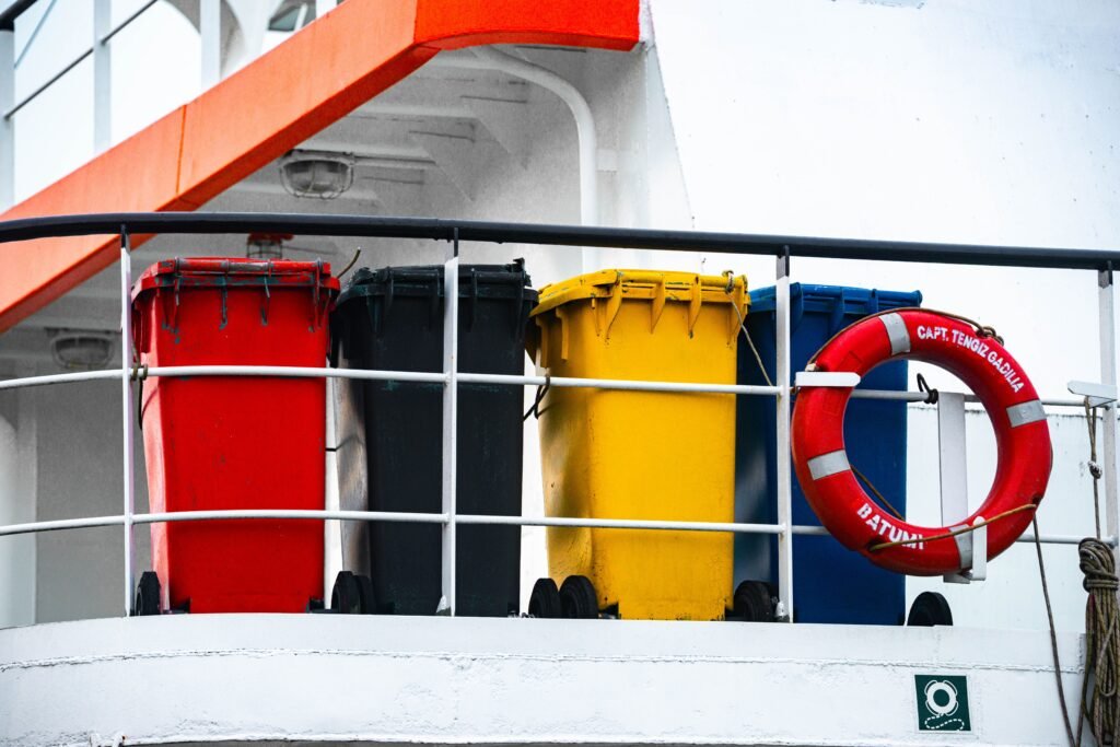 Four colorful waste bins and a lifebuoy on a ship's deck, adding vibrant contrast.