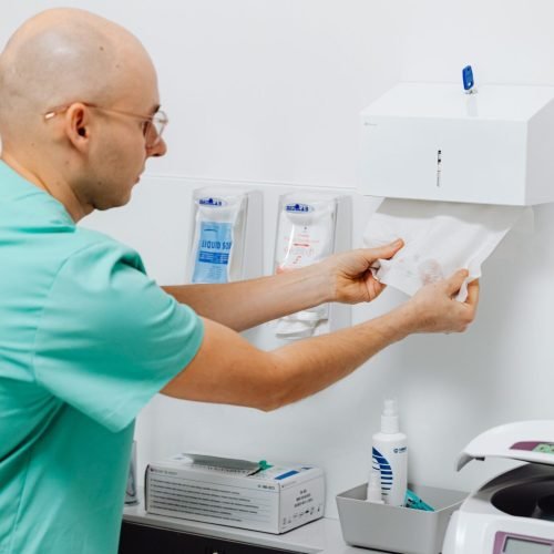 A dentist in a clinic preparing materials with medical instruments visible, promoting hygiene.